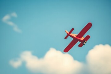 Red vintage airplane soaring in a clear blue sky with clouds