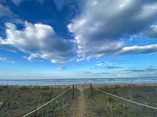 Wooden rope barrier leading to sandy coastline at Pineto Beach, cloudy Abruzzo landscape