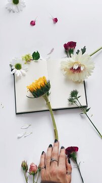 assortment of flowers, sketchbook journal flowers, peaceful morning vibes, floral journal display, charming flower arrangement, artistic morning setup, vibrant flowers on journal, serene floral compos