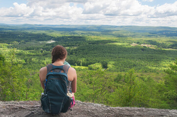 female hiker sitting on rocky cliff at Jugs End in Egermont Massachusetts