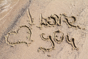 The words “I love you” written in soft sand, a simple and heartfelt message in nature.