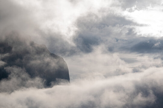 Panorama of a rugged mountain exposed between mist and clouds with partially transparent sky - Powered by Adobe