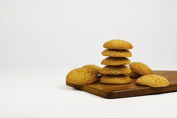 A stack of cookies on a wooden cutting board. The cookies are all the same size and are piled on...