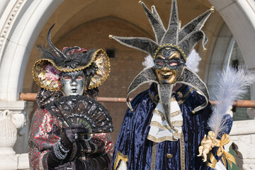 Venice, Italy - People dressed in carnival masks are photographed by tourists in the scenery of the ancient Venetian palaces
