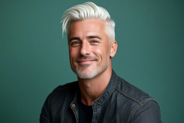 A confident and poised man in a professional setting. Visual idea of style for aging men. Green solid background. Chic men's slick back with fade haircut - midlife white man with white hair.