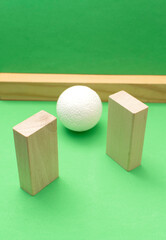 Still life with wooden blocks and a a plastic foam ball on green background	