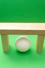 Still life with wooden blocks and a a plastic foam ball on green background	