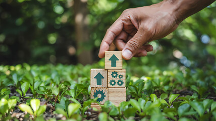 Building Sustainable Growth Hand Placing Arrow Block on Stacked Gear Blocks Amongst Lush Greenery, Illustrating Business Strategy and