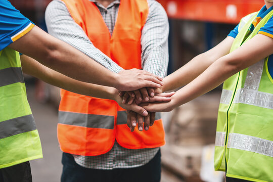 asian warehouse team worker showing spirit. logistic shipping worker with safety helmet and vest gesture. female and male team work employee group showing team spirit workplace for effectively work