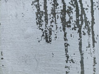 Obraz premium Grungy White Wall with Dark Stains and Brush Texture. Close-up of a white wall surface with dark paint drips, stains, and textured brush strokes. Ideal for grunge design backgrounds