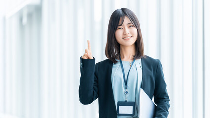 ノートパソコンを持って案内をする笑顔の女性・ビジネスウーマン