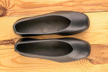 Women's black shoes on a wooden table, close-up, top view.