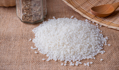 Background image of a handful of Japanese koshihikari rice poured onto a burlap cloth on the table