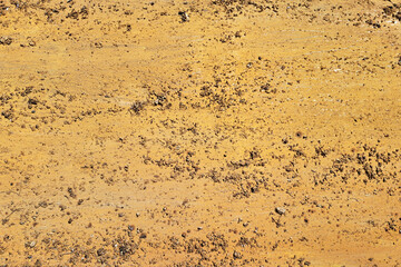 Dry sand surface texture. Yellow earth ground. Natural dirt background. Granular soil closeup. Rough desert floor. Arid terrain photo. Construction site sand. Brown dusty texture.
