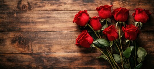 Red roses bouquet arranged on a rustic wooden surface background.
