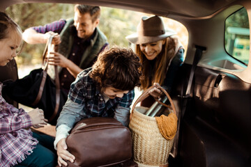 Family packing car trunk together for weekend road trip adventure