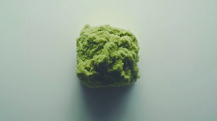 A close-up shot of a dollop of wasabi paste on a white background. The vibrant green color and textured surface are highlighted.