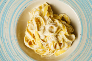 Classic spaghetti cacio e pepe with grated cheese on a blue-striped plate