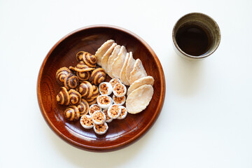 白背景の木のお皿に入ったかりんとう、生姜煎餅などの和菓子(お茶菓子) と日本茶　俯瞰撮影