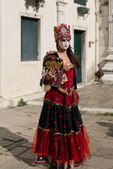 Obraz premium Venice, Italy - People dressed in carnival masks are photographed by tourists in the scenery of the ancient Venetian palaces