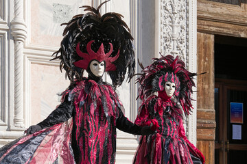 Fototapeta premium Venice, Italy - People dressed in carnival masks are photographed by tourists in the scenery of the ancient Venetian palaces