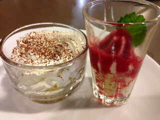 Delicious double colored strawberry cheese cake, panna cotta, Banoffee, mousse pudding with rec cherry color topping on white ceramic plates 