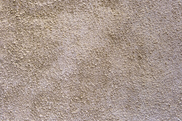 A wall with a textured surface. The wall is tan in color. The texture is rough and uneven.