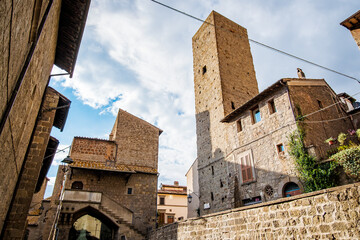 Low angle view of a medieval tower rising above the stone houses of the San Pellegrino district in Viterbo, Italy, creating a captivating glimpse into the city's rich history