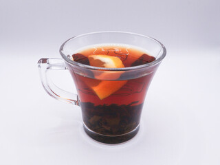 Glass cup of black tea, with a slice of lemon, side view, white background
