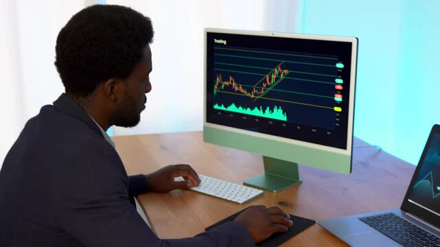 African trader man working at home doing blockchain research with computer and laptop - Finance and business concept 
