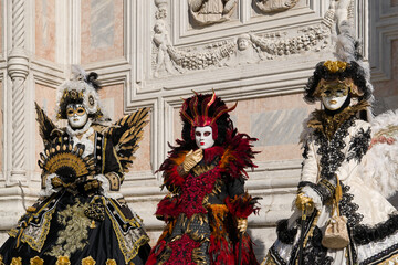 Venice, Italy - People dressed in carnival masks are photographed by tourists in the scenery of the ancient Venetian palaces