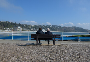 Un couple sénior assis sur un banc face à la mer en Bretagne