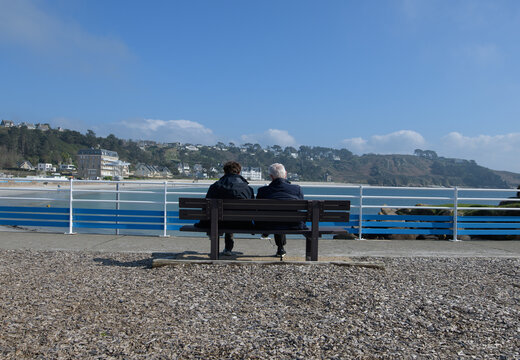 Un couple sénior assis sur un banc face à la mer en Bretagne