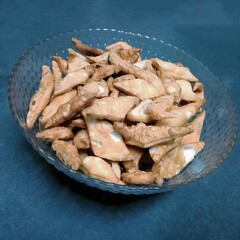 A bowl of crispy, golden Namak Para—flaky, savory Indian snacks seasoned with spices like cumin or ajwain. Perfectly fried treats enjoyed with tea or during festive celebrations.t