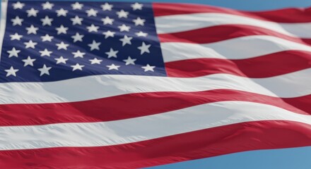 American Flag Waving in Blue Sky - Close-up of an American flag waving proudly against a clear blue sky. Patriotic symbol of freedom