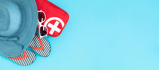 Beach holiday. Top view of a red first aid kit with a white cross, hat, sunglasses and flip-flops. Top view, flat lay.