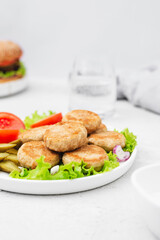 Vegan meat patties that cook like meat and have the same texture with green salad on a light concrete background. Delicious vegan food