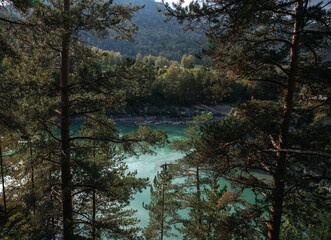 Obraz premium Majestic river flowing through a lush forest landscape with a small speedboat cutting across the water. Surrounded by towering cliffs and trees, creating a serene escape.