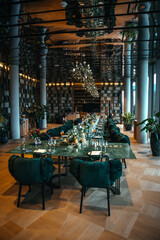 Luxurious dining room featuring a long table with elegant floral centerpieces, green cushioned chairs, and ambient decorative lighting, ideal for upscale dining experiences or events.