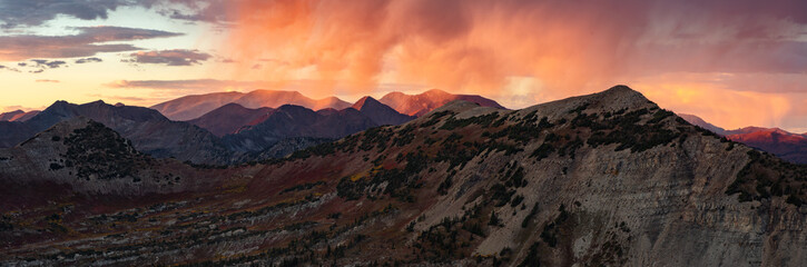 Obraz premium Colorful rain shower above Peeler Peak and the Elk Range mountains outside of Crested Butte Colorado during a dramatic autumn sunset.