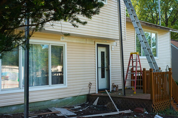 Installation of new vinyl siding is nearing completion on the front of a split-level house.