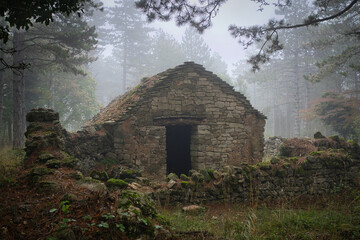 eerie view of an ancient quarrystone dwelling in the mountains of southern france on a misty autumn...