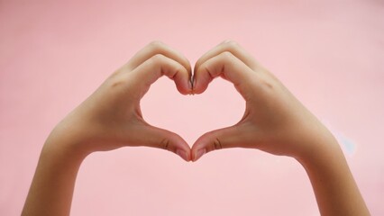 Fototapeta premium A person forming a heart shape with their hands, a romantic and intimate gesture