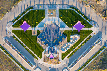 Large park with a fountain in the center and a purple tent in the background