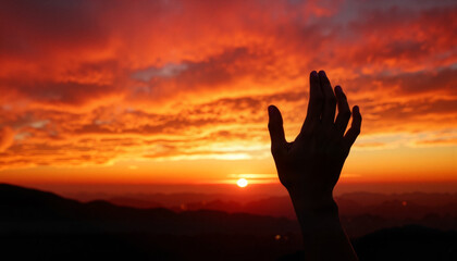 Silhouette of a raised hand in prayer against a dramatic sunset skyline for spiritual blogs, motivational websites, meditation materials, and social media content