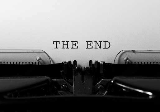 Typewriter types The End on paper in black and white showing vintage typewriter with text on paper representing completion and finality of a project or story with typewriter font - Powered by Adobe