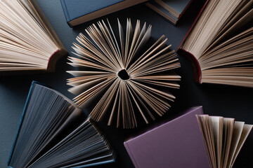 Overhead shot of several open books fanned out, showcasing aged paper texture and diverse bookbinding colors, representing knowledge, reading, and literature