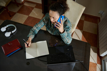 Woman Multitasking on Phone and Notebook at Home Office Desk