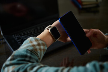 Tech-Savvy Individual Using Smartwatch and Smartphone in Modern Workspace