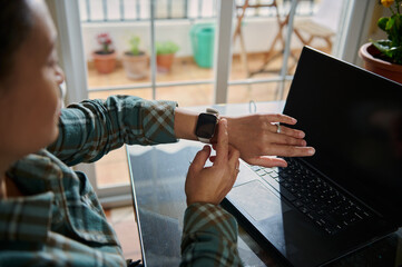 Person Using Smartwatch While Working on Laptop at Home Office